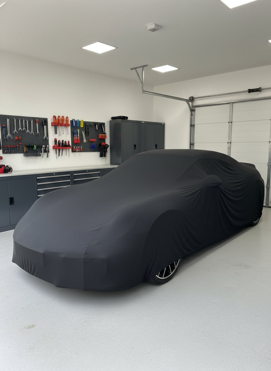 Car covered with a black car cover in a driveway